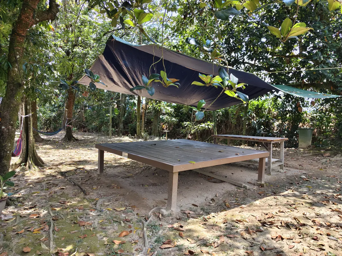 Meja kayu panjang di bawah teduhan kanvas antara pokok